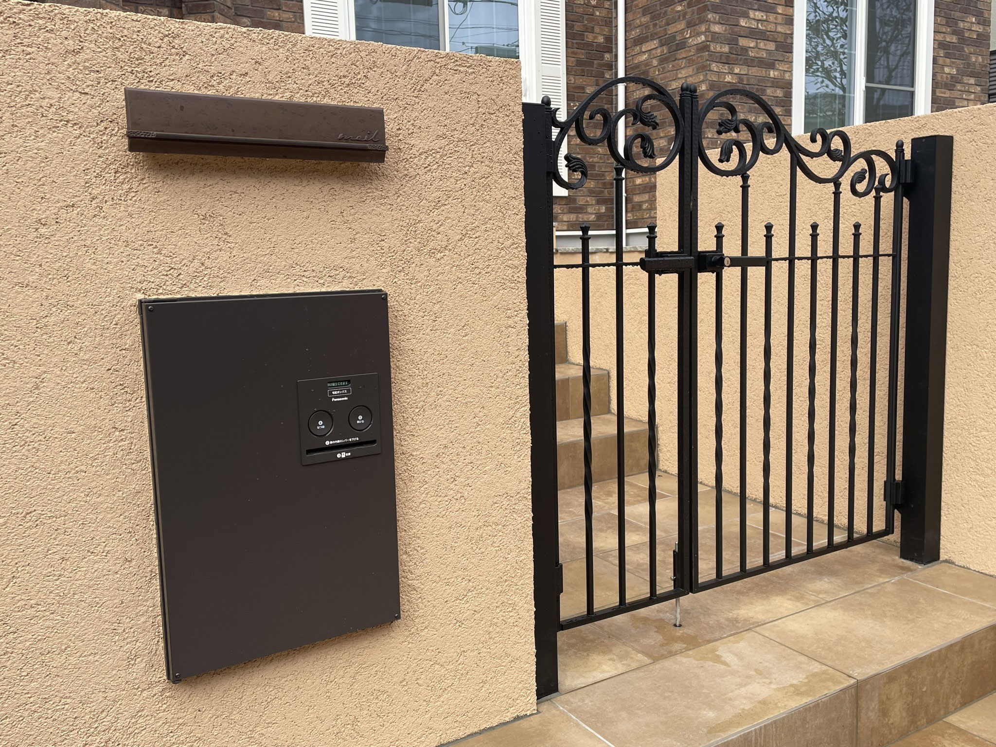 黒い鋳物門扉をピンクベージュの門塀に組み合わせて洋風さを強調した施工後アフター画像