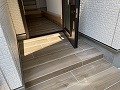 建物の中と外共に茶系ダークカラーのウッド調タイルに施工した画像/タイルは大きめなので高級感があります