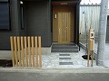 敷地と道路の境に建物の玄関と同色のベージュ角材を9本建て、機能門柱を組み合わせた外構工事の事例